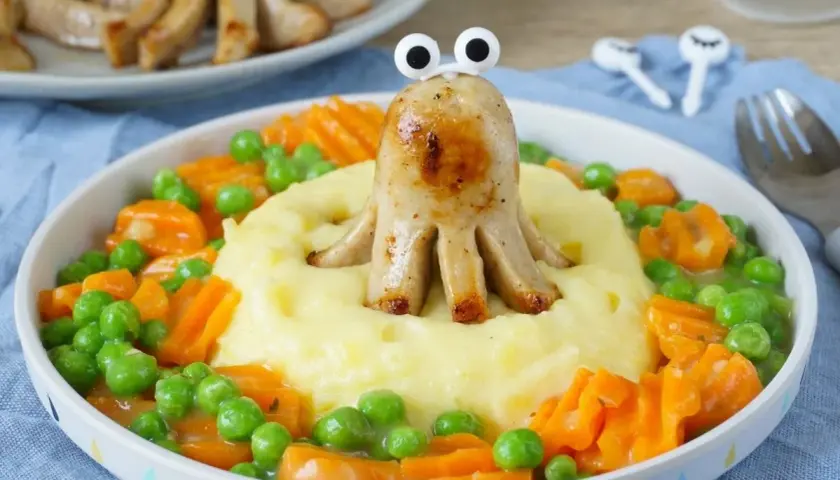 Ein lustiges Oktopus-Würstchen auf Kartoffelbrei mit Erbsen und Karotten. Ein gesundes Mittagessen für Kinder, das Spaß macht!