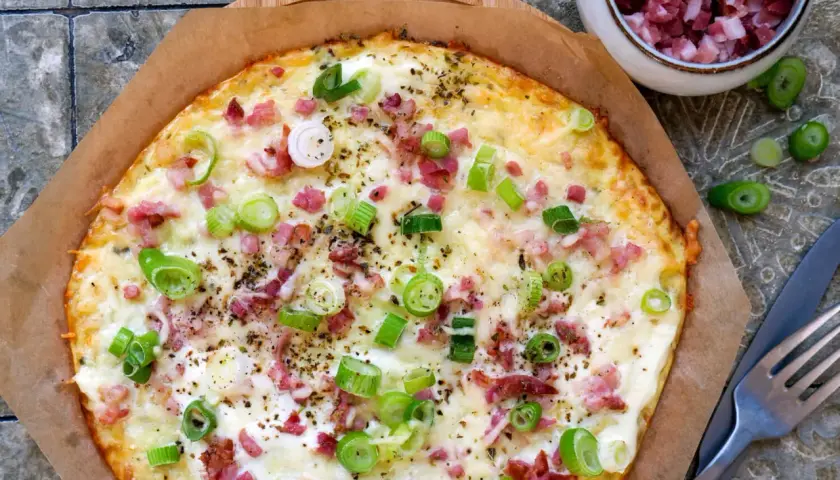 Leckerer low carb Flammkuchen mit Speck und Frühlingszwiebeln, goldbraun gebacken und bereit zum Genießen.