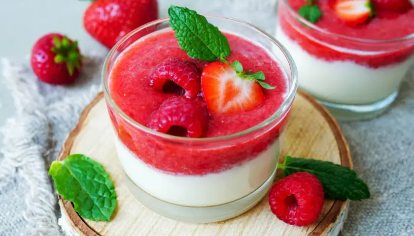 Zwei Gläser mit schnellen Desserts im Glas mit Joghurt, garniert mit frischen Beeren und Minze.
