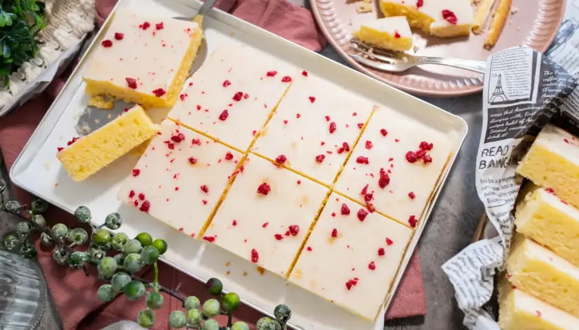 Saftiger veganer Kuchen mit weißer Glasur und roten Beerenstückchen, perfekt für jeden Anlass.