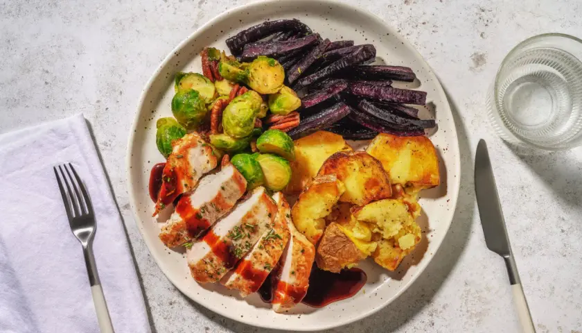 Ein Teller mit gebratenem Hähnchen, Rosenkohl, lila Karotten und Kartoffeln. Perfekt für alle, die **high carb rezepte** lieben und eine sättigende Mahlzeit suchen.