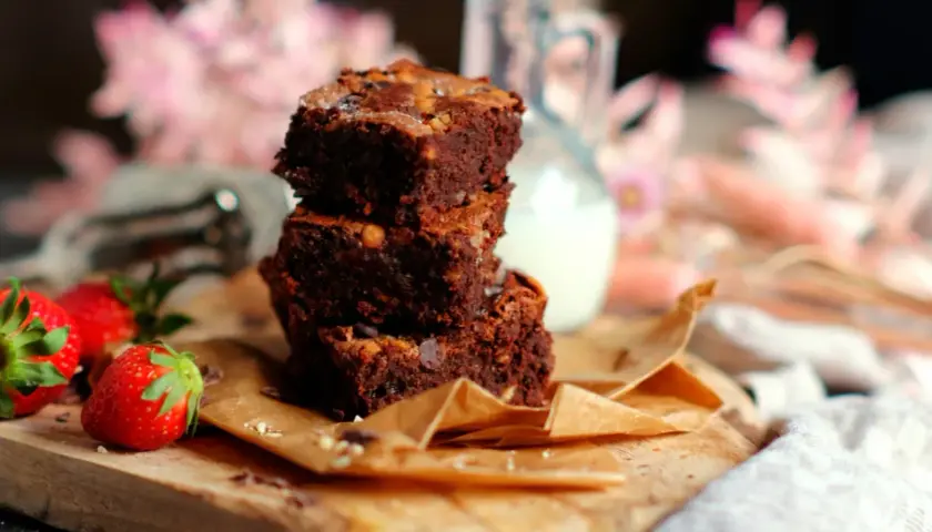 Gestapelte Brownies mit Nüssen und Schokostückchen, dazu frische Erdbeeren. Ein perfektes brownie rezept für Genießer.