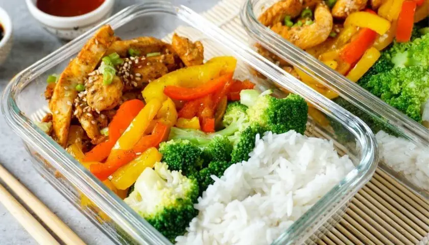 Zwei Glasbehälter mit Hähnchen, Paprika, Brokkoli und Reis. Perfekt für ein gesundes low carb mittagessen.