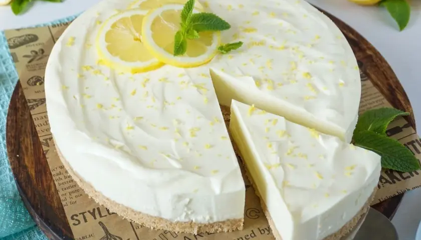Cremige Philadelphia Torte mit Zitronenscheiben und Minze, ein Stück wurde bereits angeschnitten.