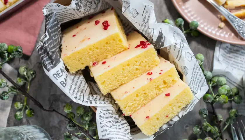 Saftige Kuchenstücke mit weißer Glasur und roten Streuseln, inspiriert von einem Tassenkuchen Rezept Blech.