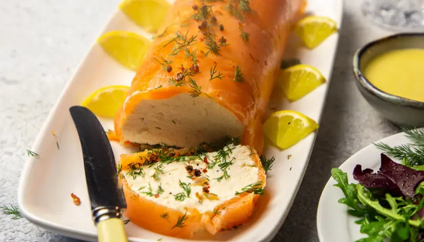 Eine köstliche Vorspeise mit Lachs: ein zarter Lachsrolle gefüllt mit einer cremigen Masse, garniert mit Dill und Zitrone.