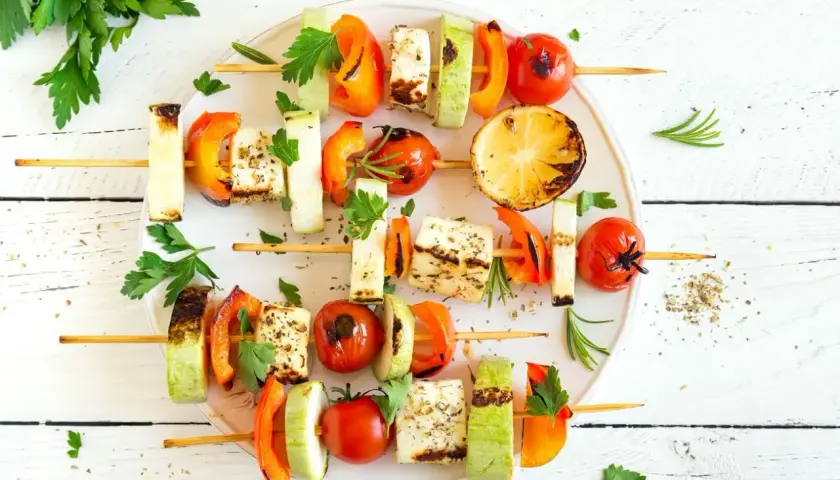 Gegrillte Spieße mit Halloumi, Paprika, Zucchini und Tomaten – köstliche vegetarische Gerichte, garniert mit frischer Petersilie und Rosmarin.