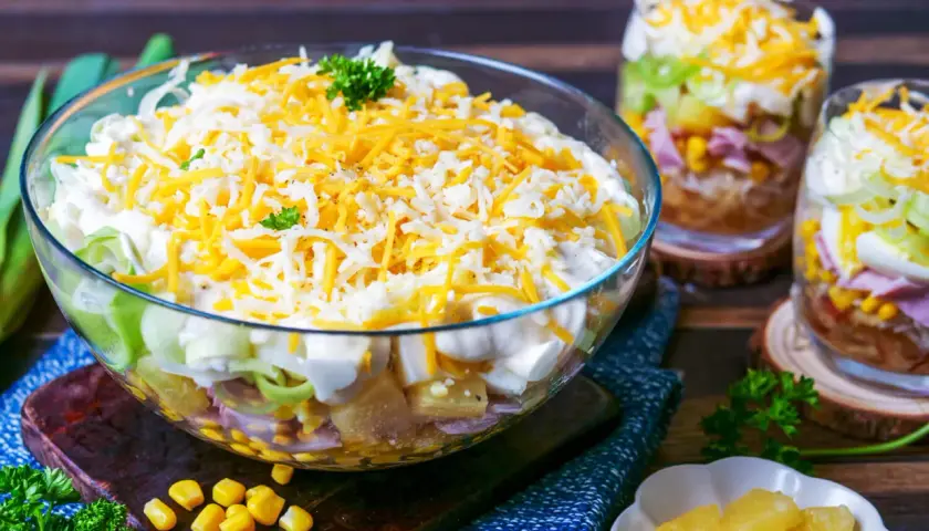 Schichtsalat-Rezept mit Miracel Whip: Ein bunter Salat aus Schichten von Gemüse, Ei, Schinken und Mais, gekrönt mit Käse.