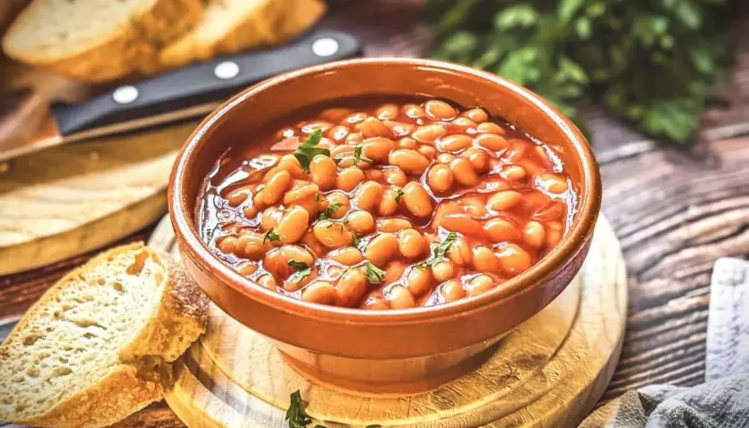 Herzhaftes baked beans rezept in einer Schüssel, garniert mit Petersilie, serviert mit frischem Brot.