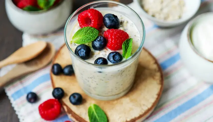 Erfrischendes Glas Overnight Oats mit Joghurt, garniert mit frischen Beeren und Minze. Perfekt für einen gesunden Start in den Tag.