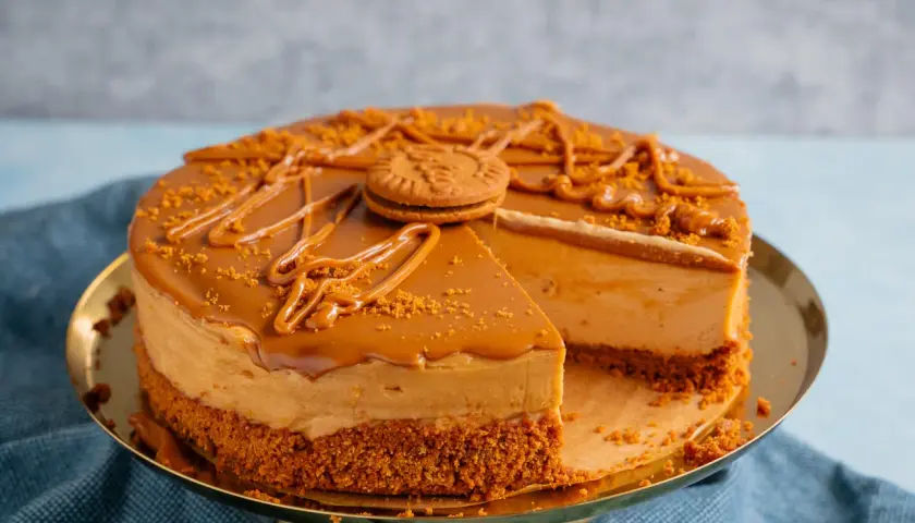 Ein köstlicher Lotus Cheesecake mit Karamellglasur und zerbröselten Keksen, dekoriert mit einem ganzen Keks.