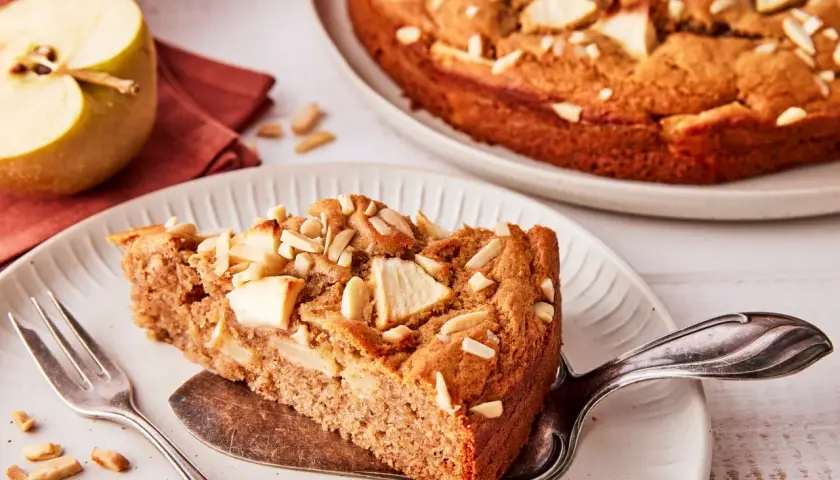 Ein Stück saftiger Apfelkuchen ohne Zucker, garniert mit Mandelblättchen und Apfelstücken. Ein Genuss für alle Sinne.