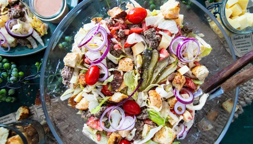 Ein üppiger Big Mac Salat mit Hackfleisch, Salat, Tomaten, Zwiebeln, Gurken und Croutons in einer Glasschüssel.