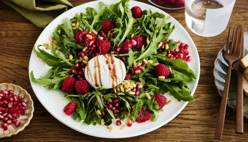 Ein frischer Salat mit Rucola, Himbeeren, Granatapfelkernen und Pinienkernen, gekrönt von cremiger Burrata. Perfekt für leichte Burrata Rezepte.