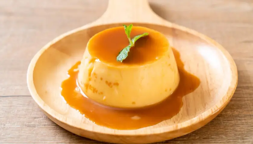 Cremiger Karamellpudding, perfekt zum Pudding selber machen. Mit Minze garniert auf einem Holztablett.