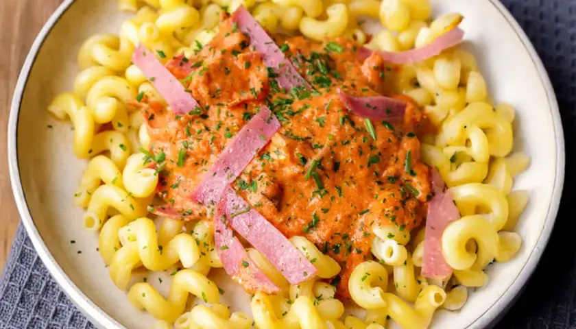 Gedrehte Nudeln mit cremiger Tomatensoße und rosa Schinkenstreifen, ein Beispiel für schnelle Pasta Rezepte.
