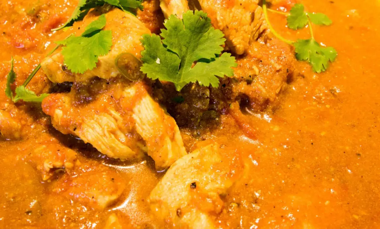 Ein köstliches indisches Curry Rezept mit zarten Hähnchenstücken in einer cremigen Tomaten-Currysauce, garniert mit frischem Koriander.