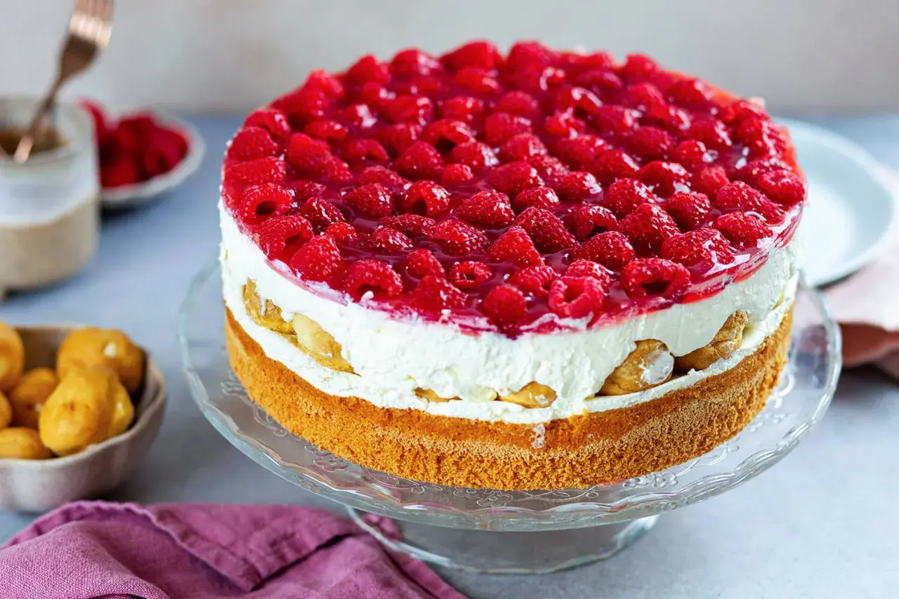 Eine köstliche Windbeuteltorte mit Himbeeren, geschichtet mit Sahne und Biskuit, verlockt zum Genuss.