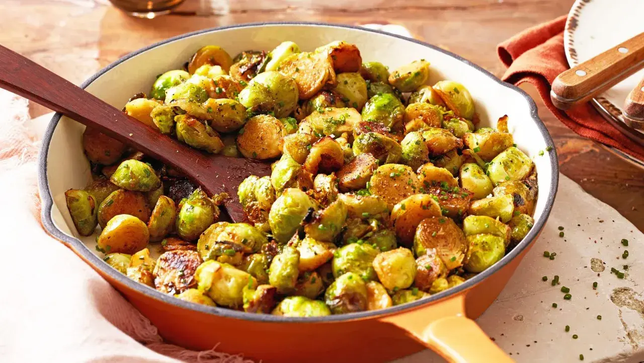Leckere Rosenkohl Rezepte Pfanne mit gebratenem Rosenkohl, Kartoffeln und Kräutern in einer Gusseisenpfanne.
