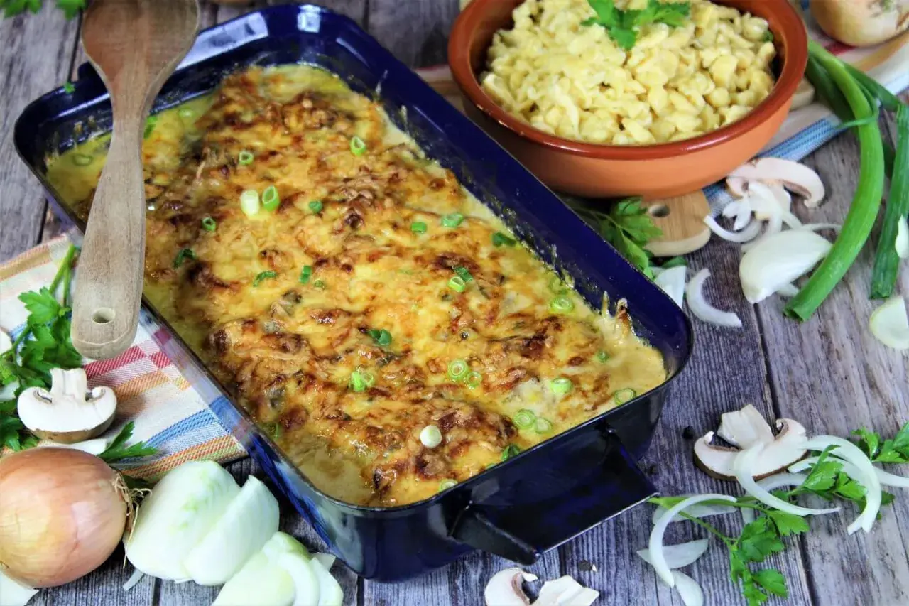 Herzhaftes Zwiebel Sahne Schnitzel mit Käse überbacken, daneben Spätzle und frische Zutaten.