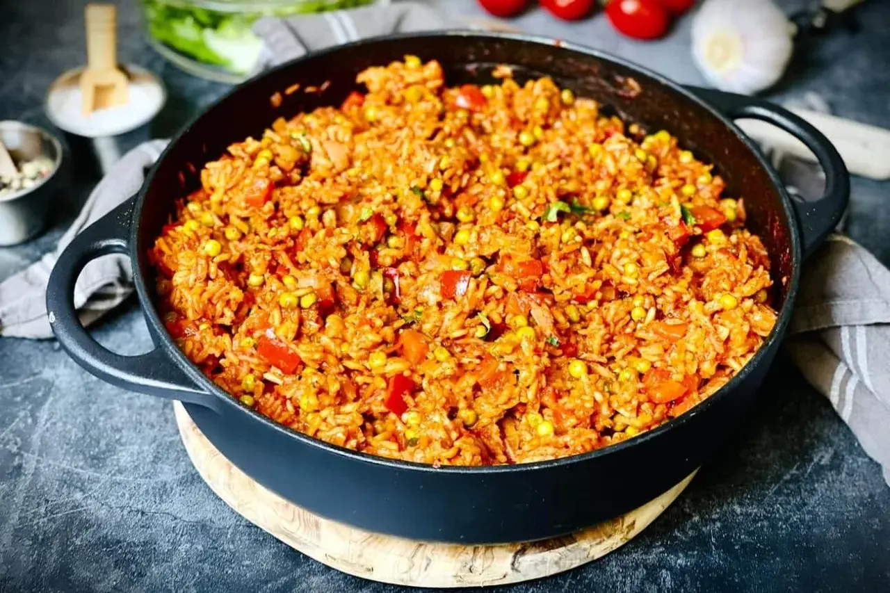 Herzhafter Djuvec Reis mit Mais und Paprika, serviert in einer Gusseisenpfanne. Ein köstliches Gericht, das nach mehr schmeckt.