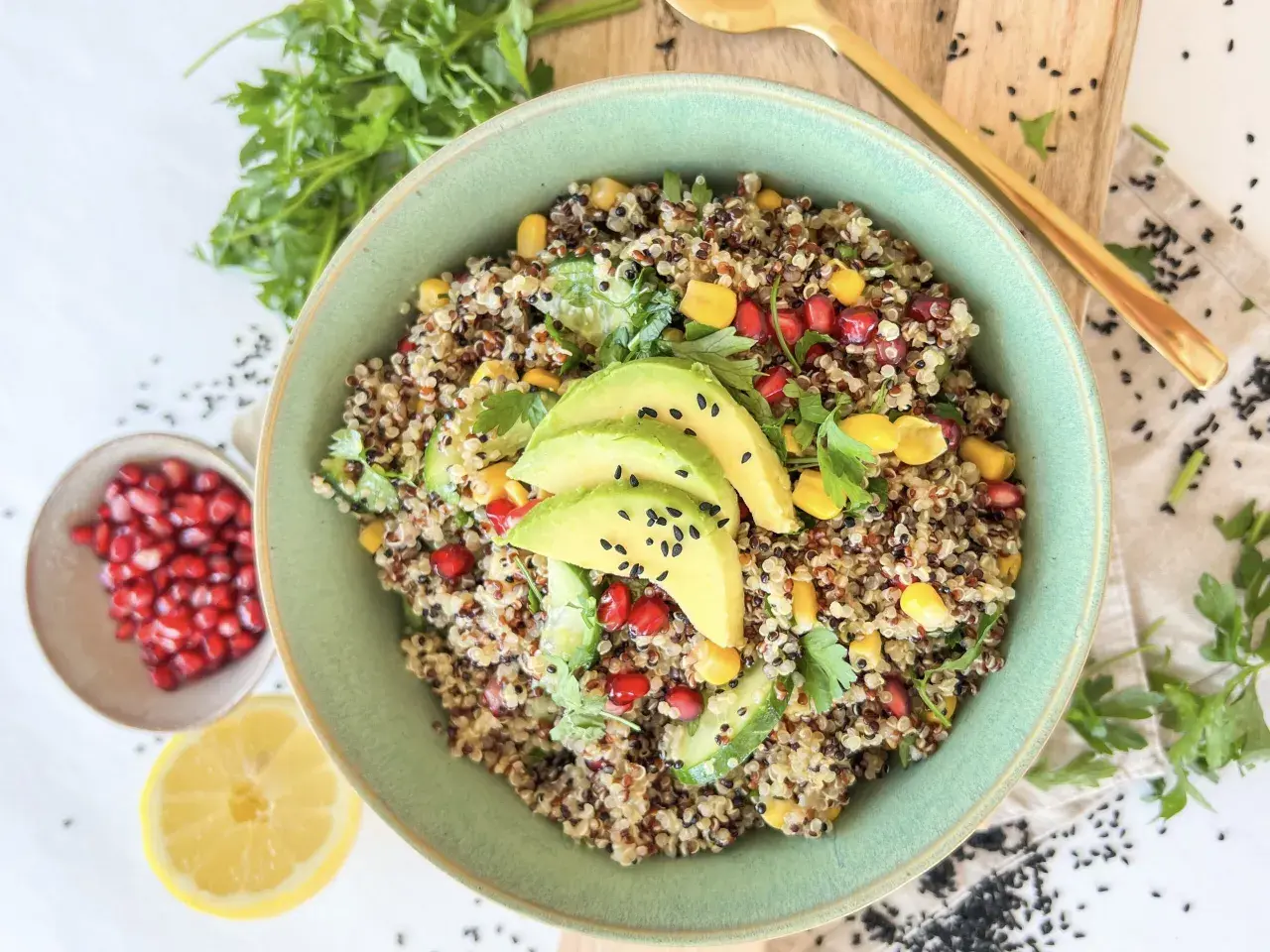 Bunter Quinoa Salat mit Avocado, Granatapfelkernen, Mais und Petersilie. Ein gesundes und erfrischendes Gericht.