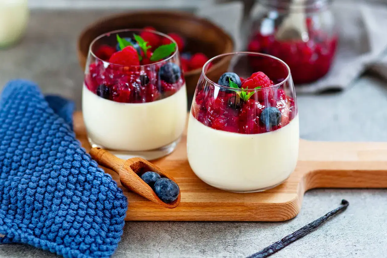 Zwei Gläser Panna Cotta mit Beerenkompott, ein perfektes Beispiel für schnelle Desserts zum Vorbereiten.