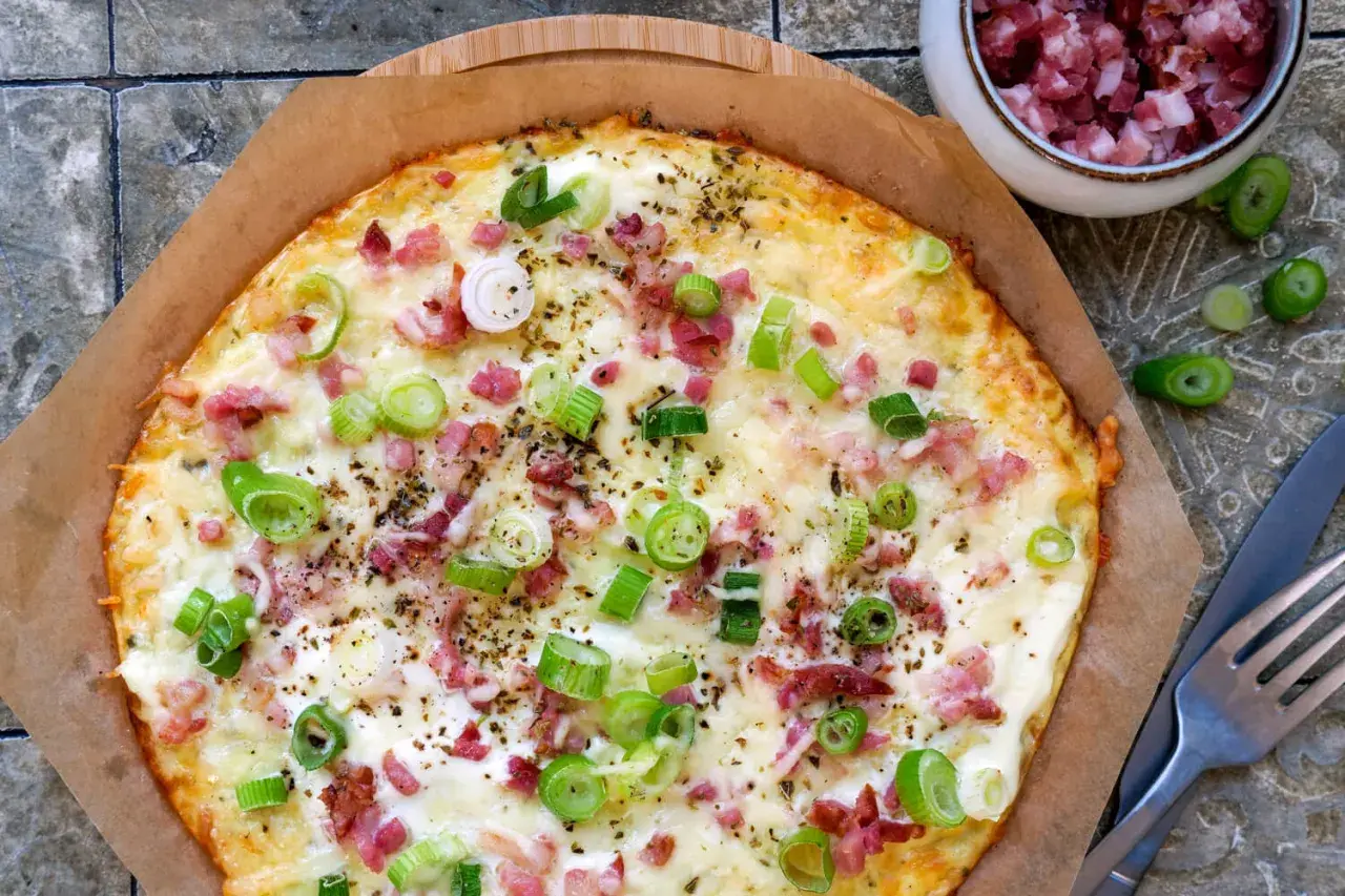 Leckerer low carb Flammkuchen mit Speck und Frühlingszwiebeln, goldbraun gebacken und bereit zum Genießen.