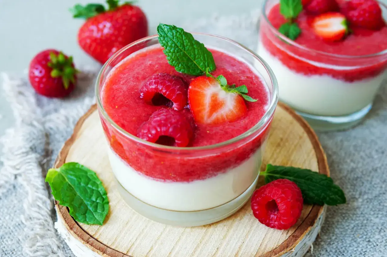 Zwei Gläser mit schnellen Desserts im Glas mit Joghurt, garniert mit frischen Beeren und Minze.
