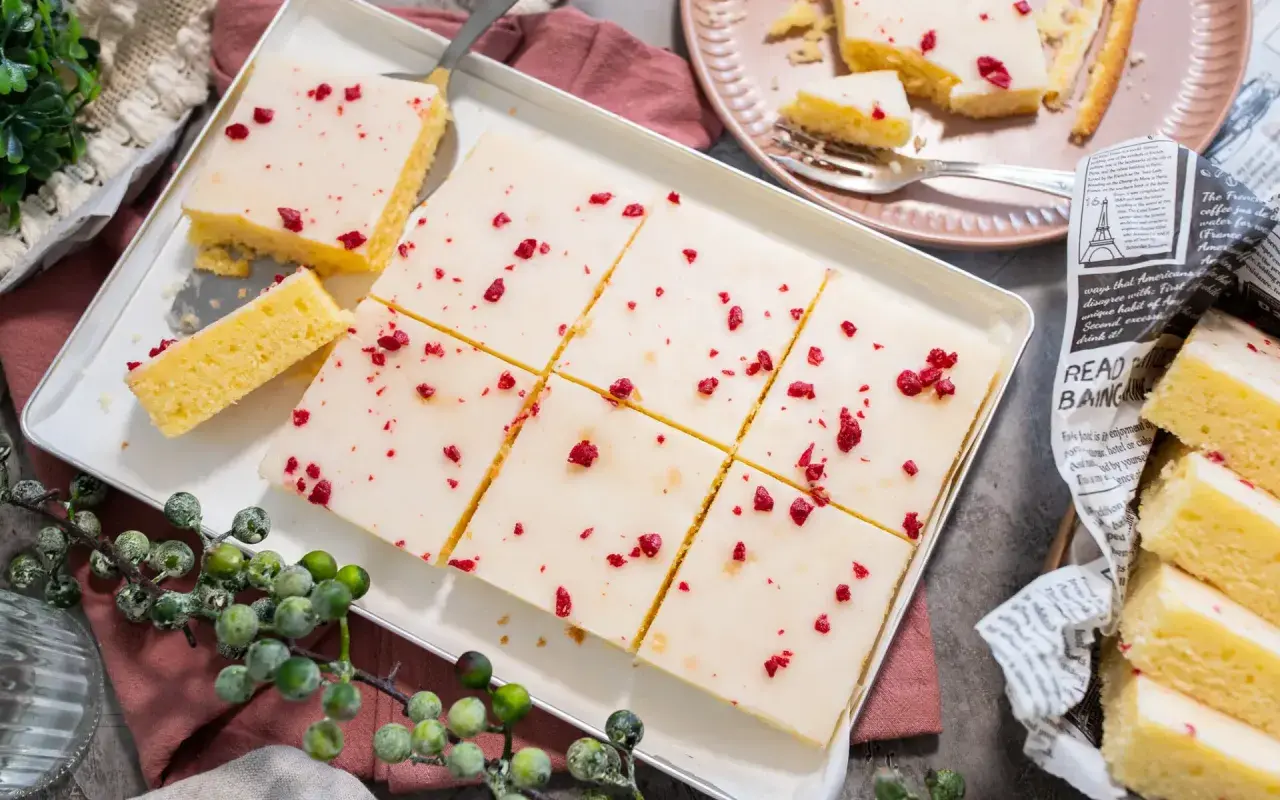 Saftiger veganer Kuchen mit weißer Glasur und roten Beerenstückchen, perfekt für jeden Anlass.