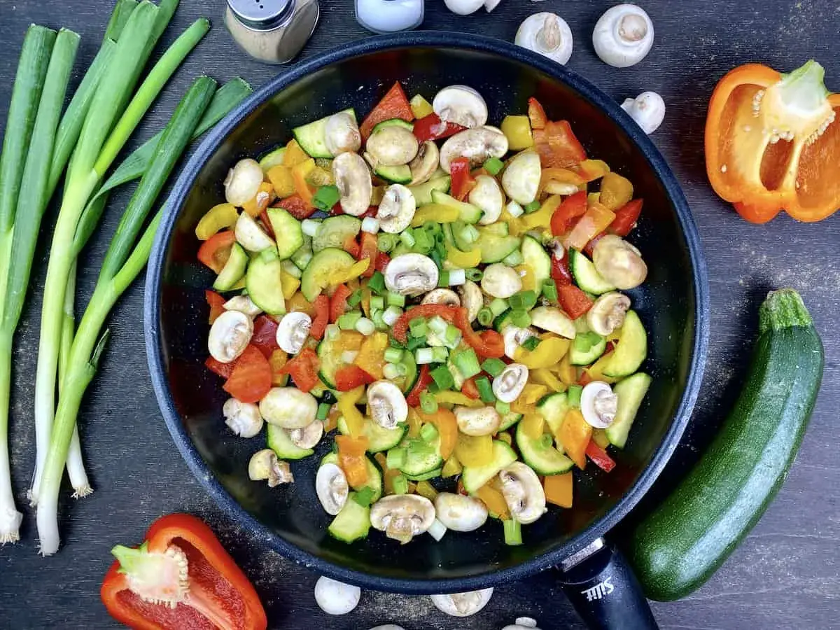 Buntes Gemüse in der Pfanne, perfekt für ein leichtes Abendessen mit wenig Kalorien. Zucchini, Paprika und Pilze werden mit Frühlingszwiebeln verfeinert.