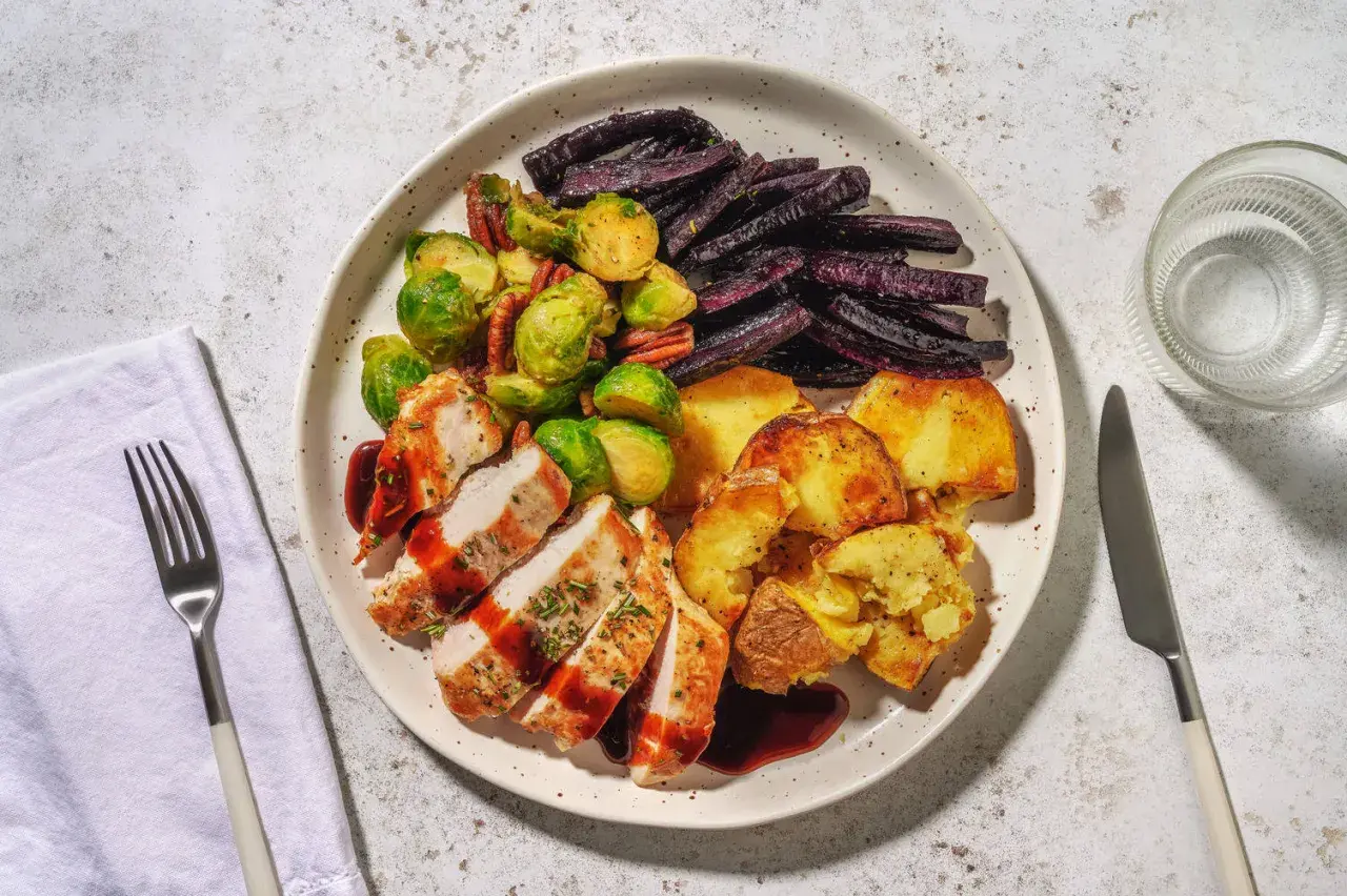 Ein Teller mit gebratenem Hähnchen, Rosenkohl, lila Karotten und Kartoffeln. Perfekt für alle, die **high carb rezepte** lieben und eine sättigende Mahlzeit suchen.