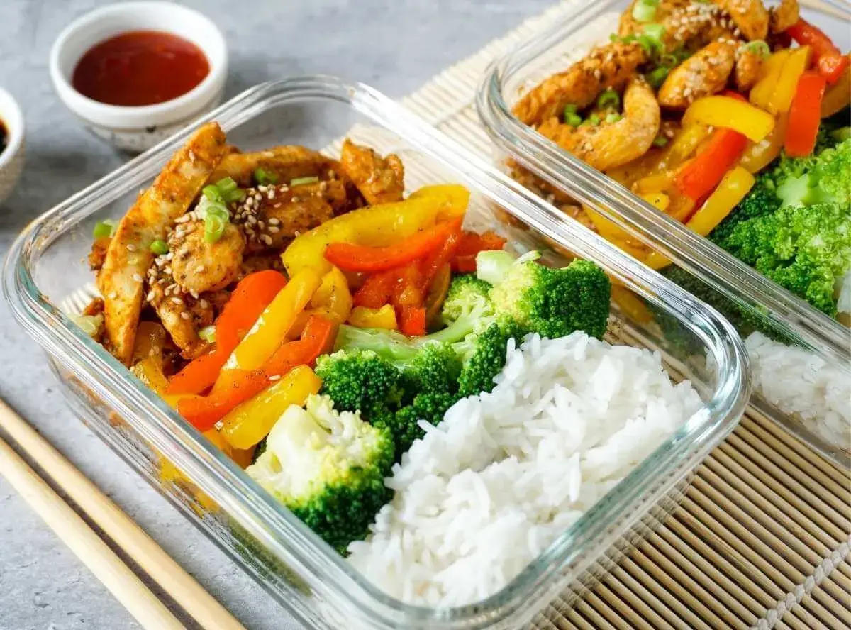 Zwei Glasbehälter mit Hähnchen, Paprika, Brokkoli und Reis. Perfekt für ein gesundes low carb mittagessen.