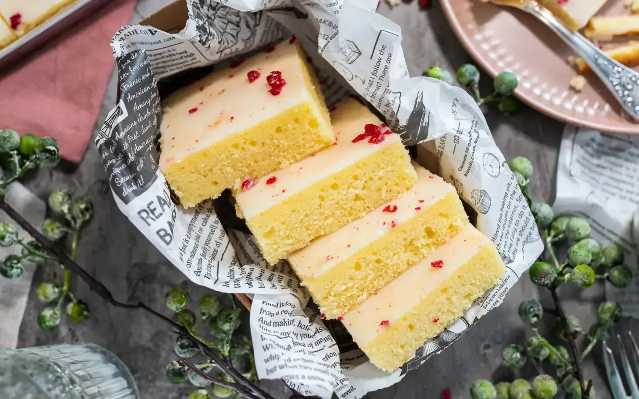 Saftige Kuchenstücke mit weißer Glasur und roten Streuseln, inspiriert von einem Tassenkuchen Rezept Blech.