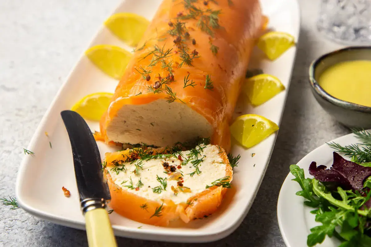 Eine köstliche Vorspeise mit Lachs: ein zarter Lachsrolle gefüllt mit einer cremigen Masse, garniert mit Dill und Zitrone.
