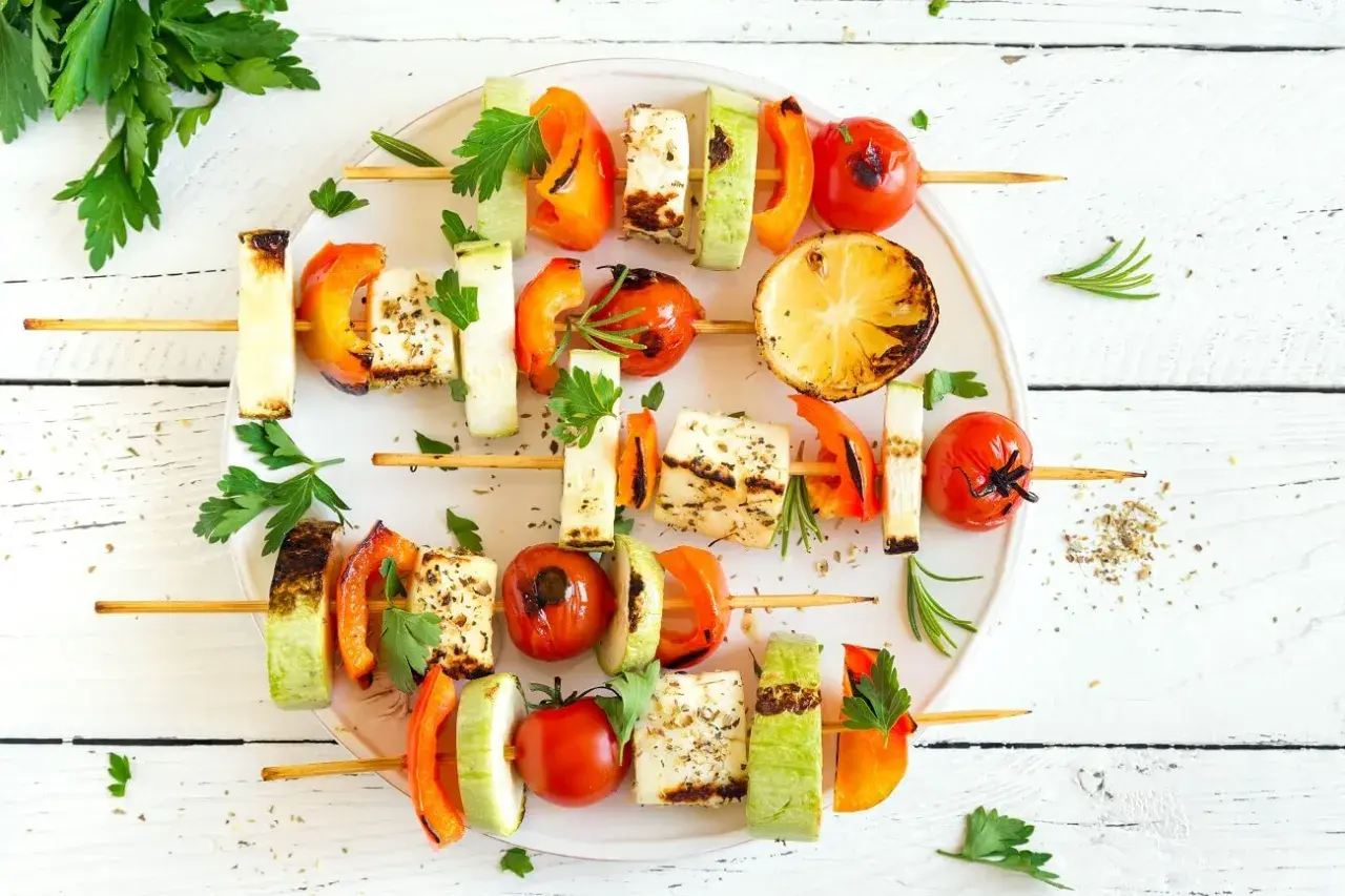 Gegrillte Spieße mit Halloumi, Paprika, Zucchini und Tomaten – köstliche vegetarische Gerichte, garniert mit frischer Petersilie und Rosmarin.