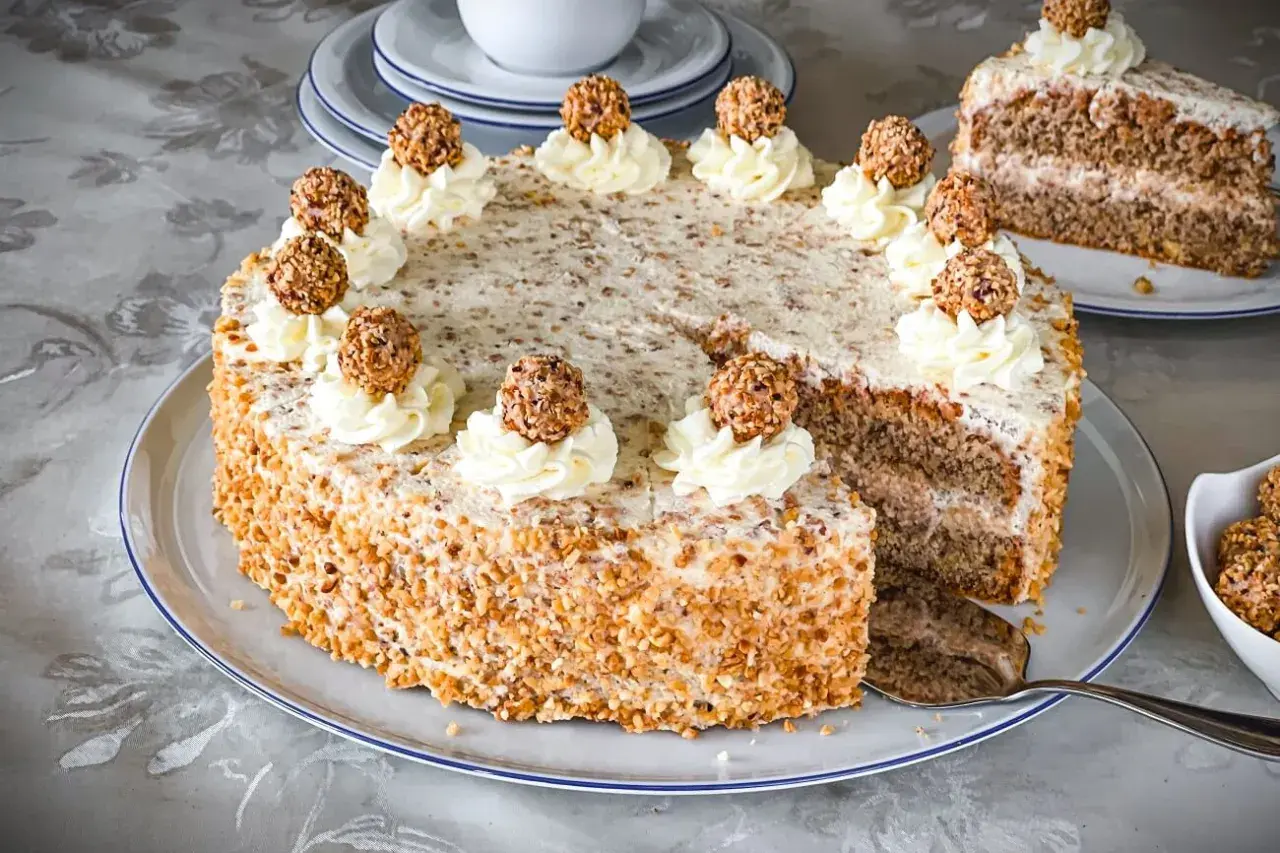 Ein köstliches Giotto Torte Rezept: Eine runde Torte mit Nuss-Crunch, verziert mit Sahnetuffs und Giotto-Kugeln.