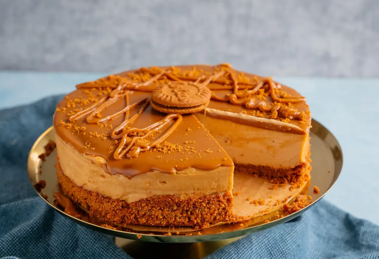 Ein köstlicher Lotus Cheesecake mit Karamellglasur und zerbröselten Keksen, dekoriert mit einem ganzen Keks.