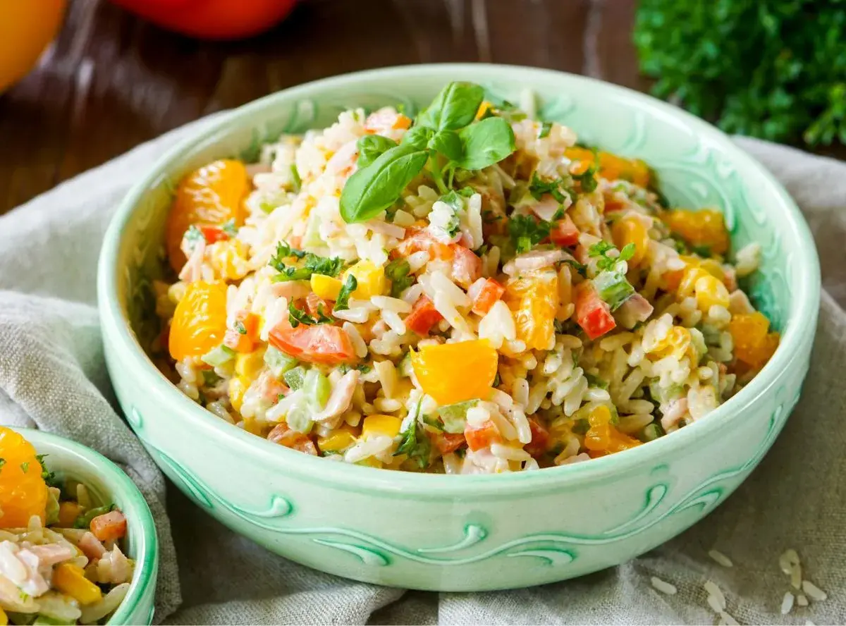 Erfrischender Reissalat mit Mandarinen, Paprika, Mais und Kräutern, garniert mit Basilikum.