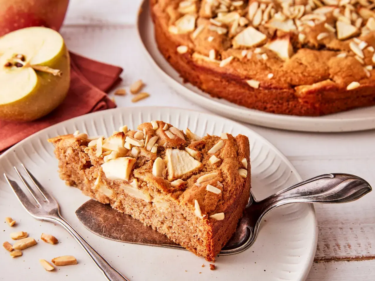 Ein Stück saftiger Apfelkuchen ohne Zucker, garniert mit Mandelblättchen und Apfelstücken. Ein Genuss für alle Sinne.