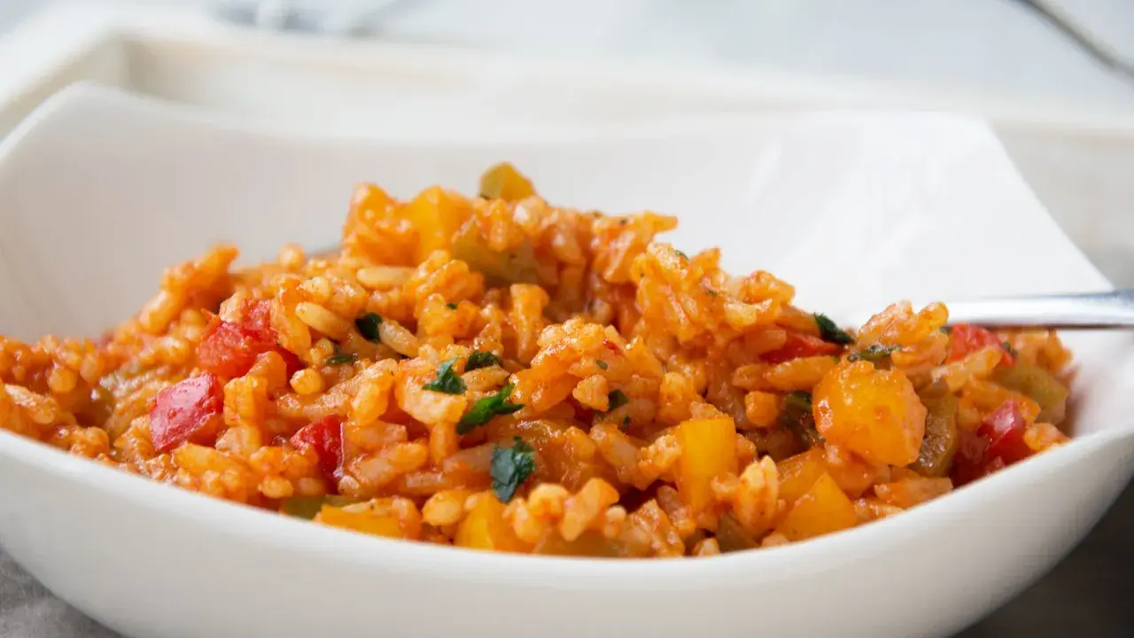 Eine köstliche Paprika Reis Pfanne mit roten und gelben Paprikastücken, serviert in einer weißen Schüssel.