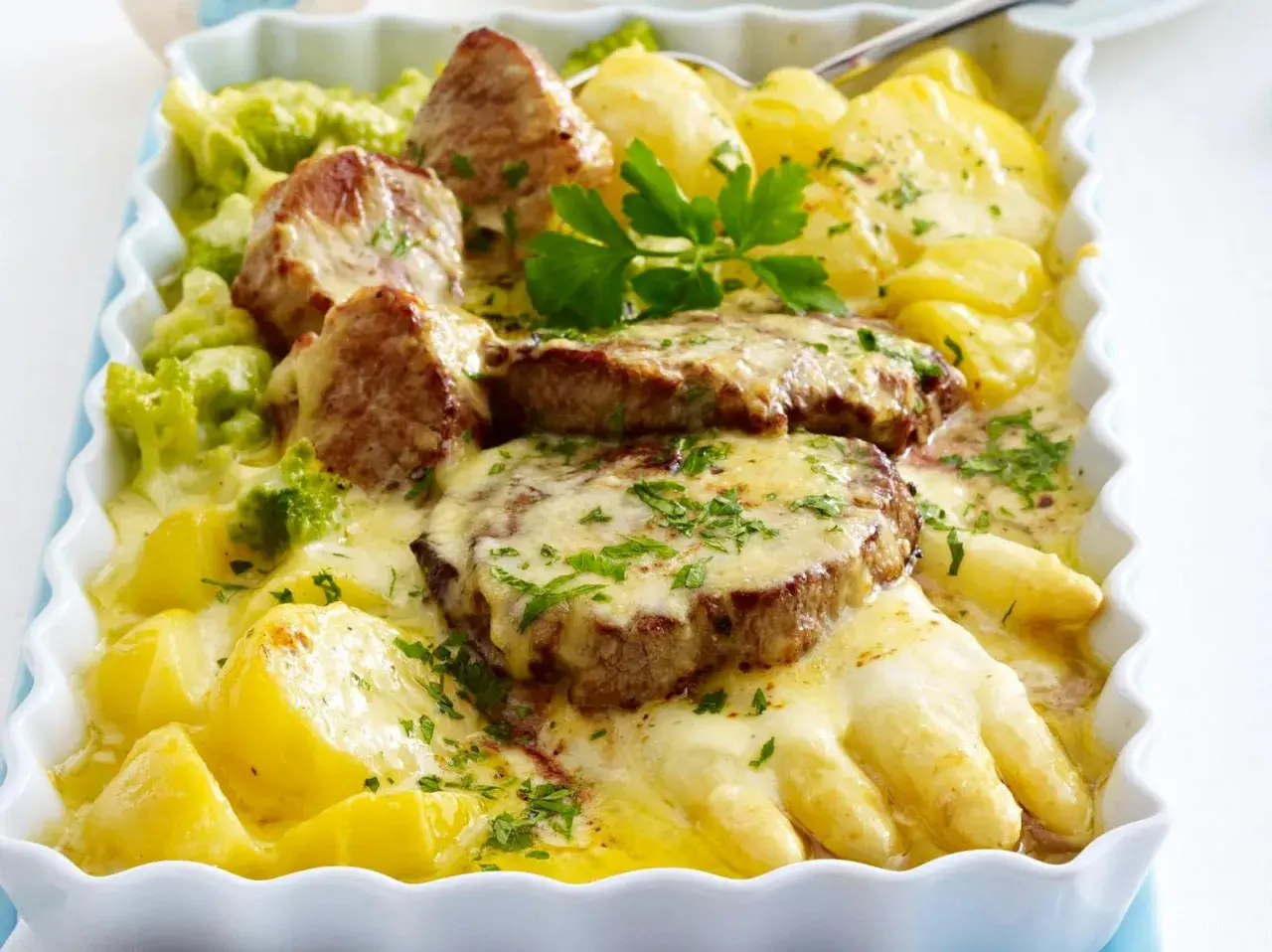Fleischscheiben mit Kartoffeln, Brokkoli und Käse überbacken. Ein Gericht, das zeigt, welches Fleisch gut zu Spargel passt.