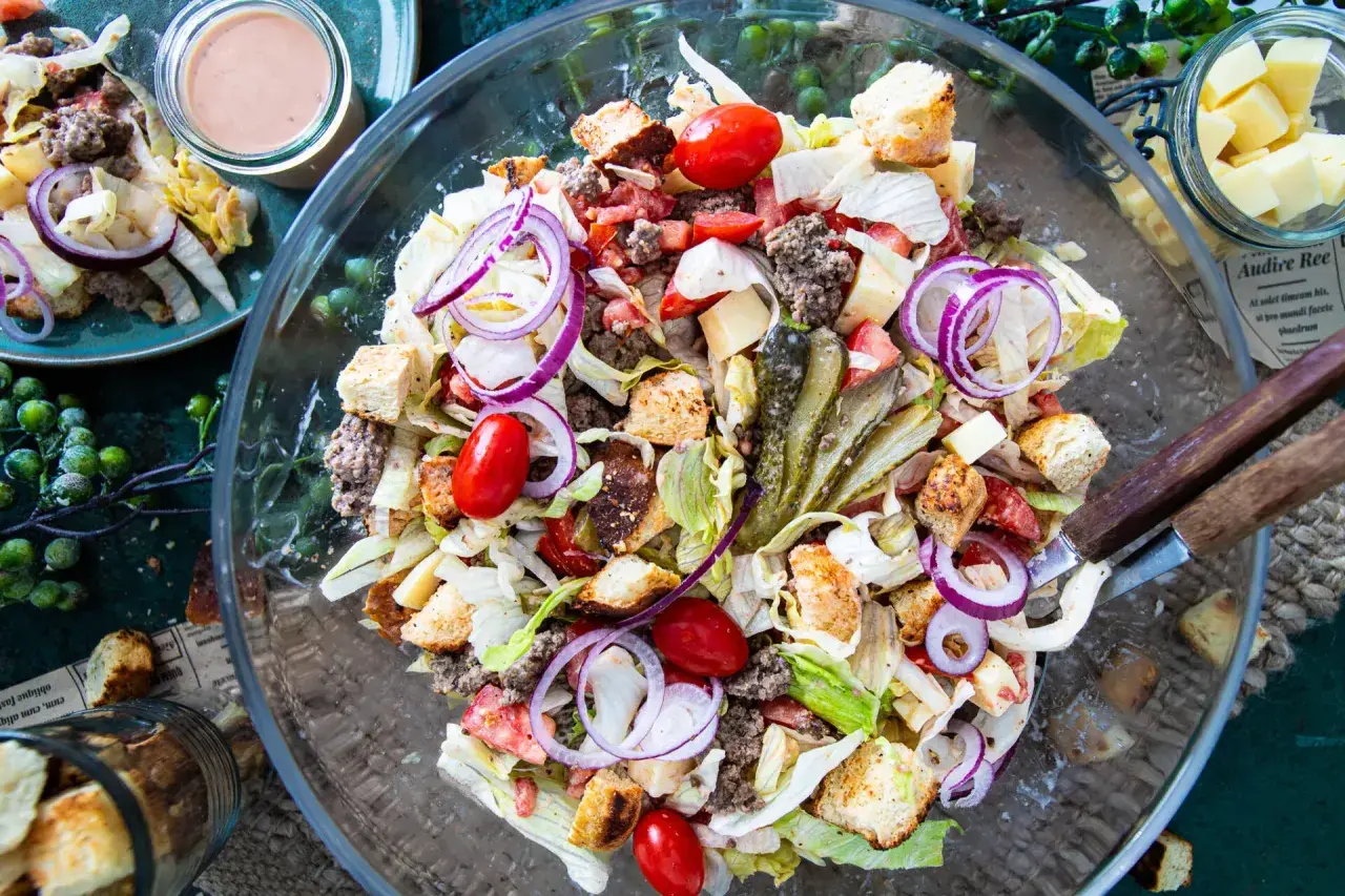 Ein üppiger Big Mac Salat mit Hackfleisch, Salat, Tomaten, Zwiebeln, Gurken und Croutons in einer Glasschüssel.