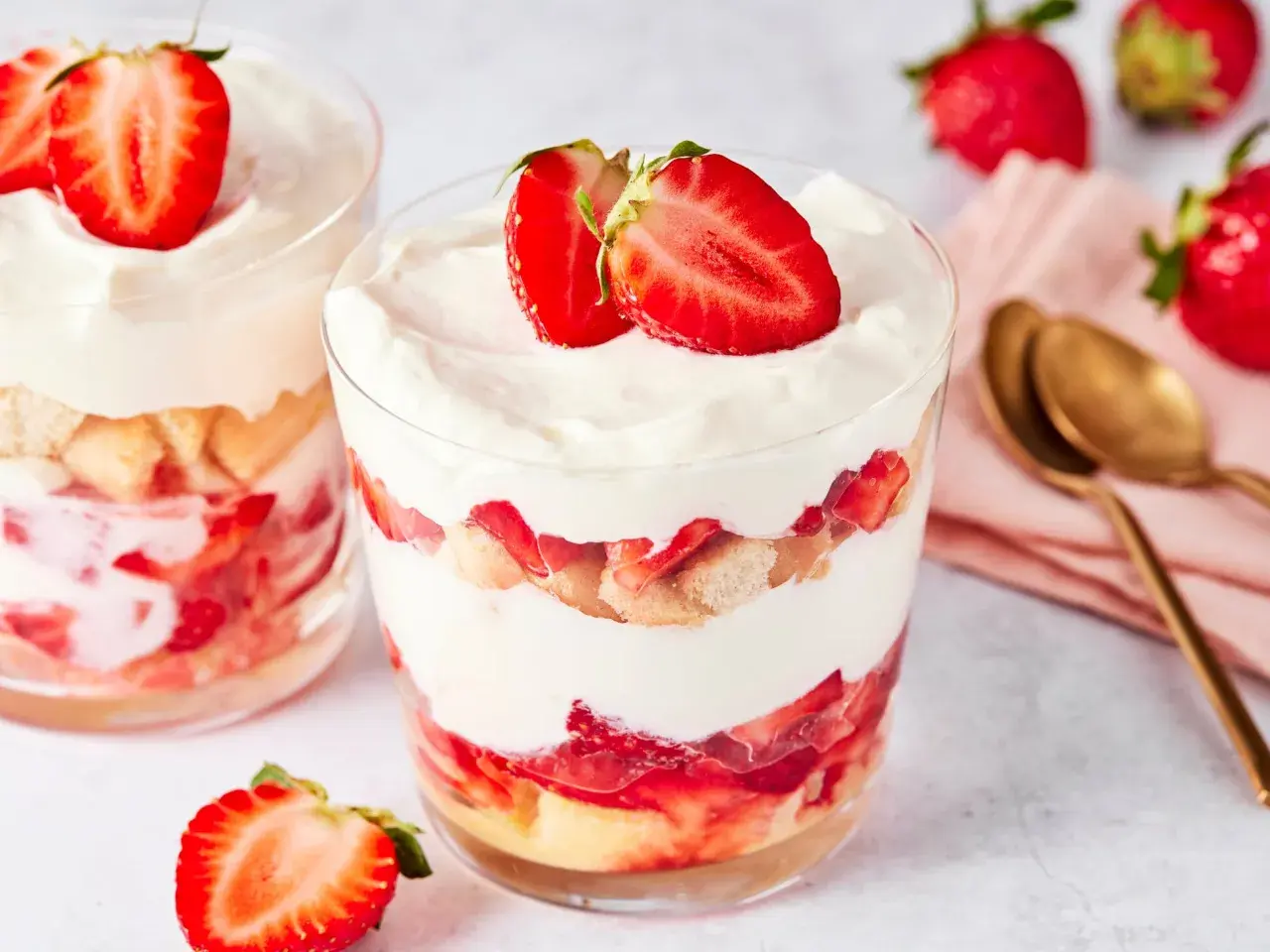 Erdbeer Tiramisu im Glas: Schichten aus Löffelbiskuits, frischen Erdbeeren und cremiger Mascarpone, garniert mit Erdbeerscheiben.