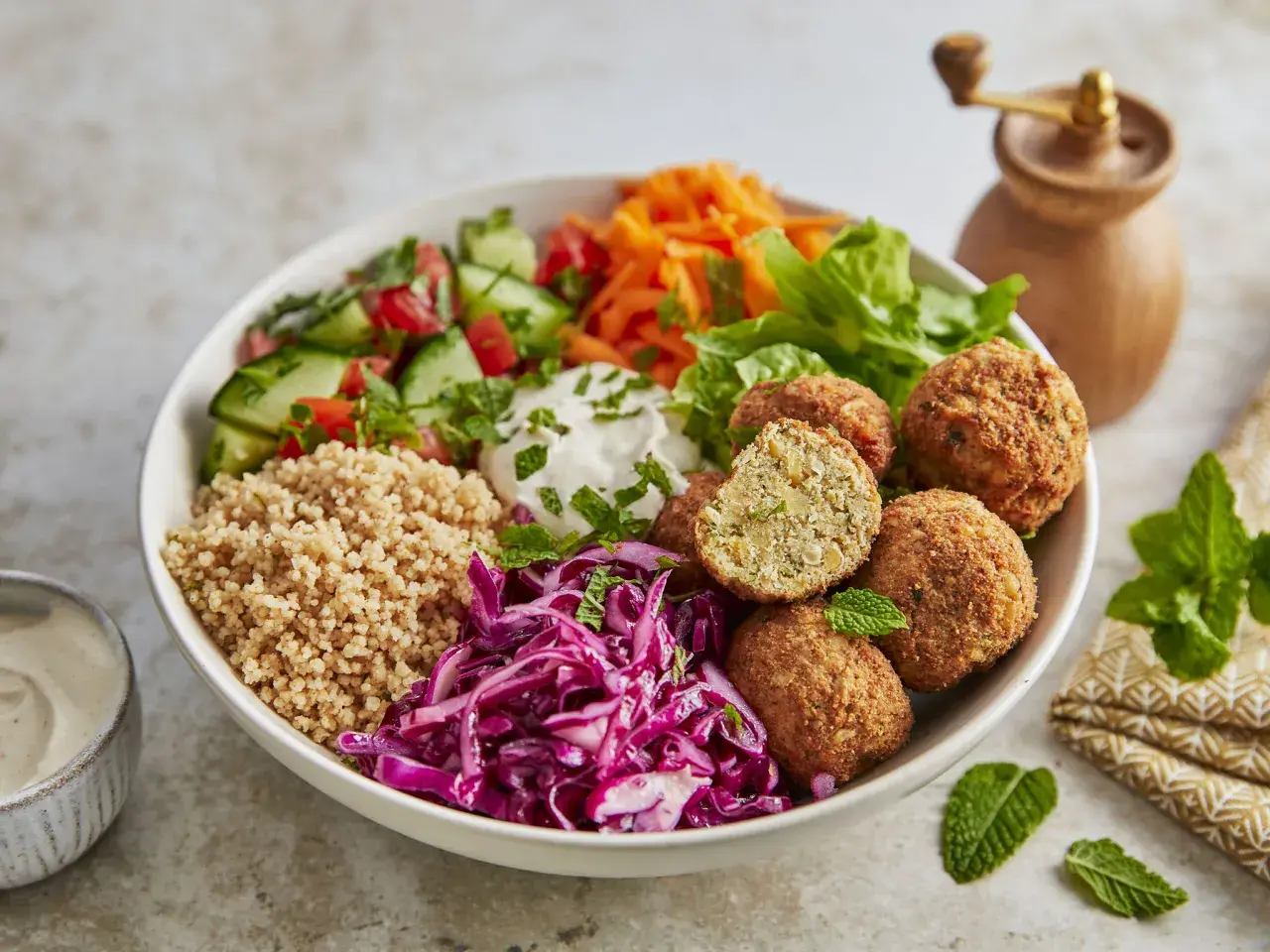 Schüssel mit Falafel, Couscous, Tomaten, Gurken, Rotkohl und Joghurt. Perfekt für gesunde Essen Rezepte.