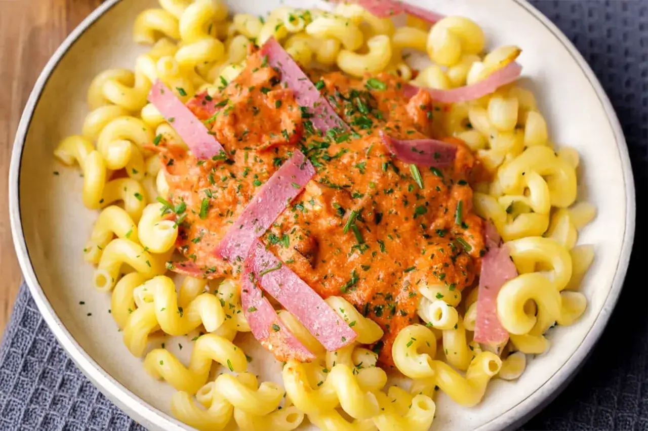 Gedrehte Nudeln mit cremiger Tomatensoße und rosa Schinkenstreifen, ein Beispiel für schnelle Pasta Rezepte.