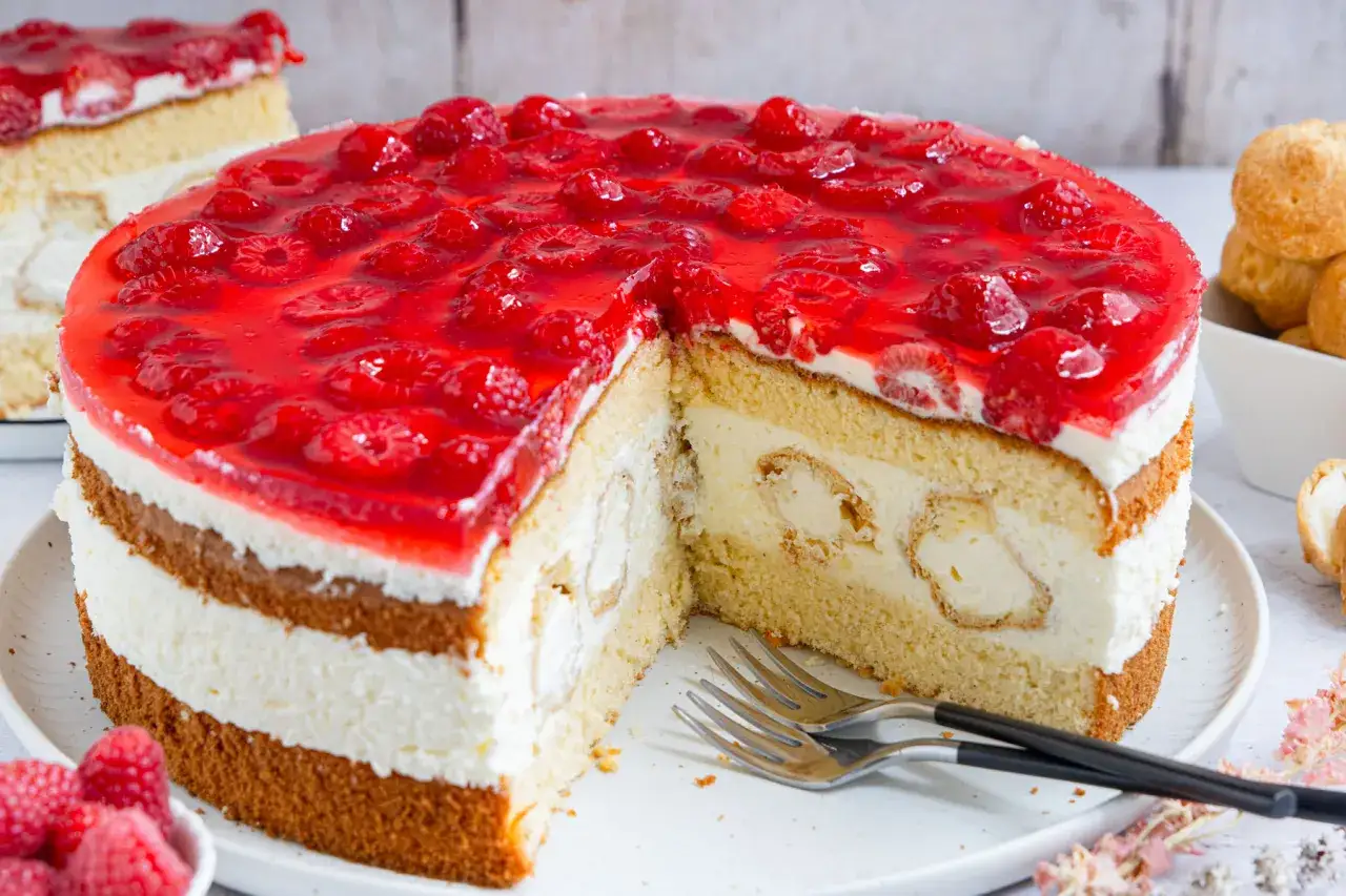 Eine köstliche Windbeuteltorte mit Himbeeren und Sahne, bereit zum Genießen.