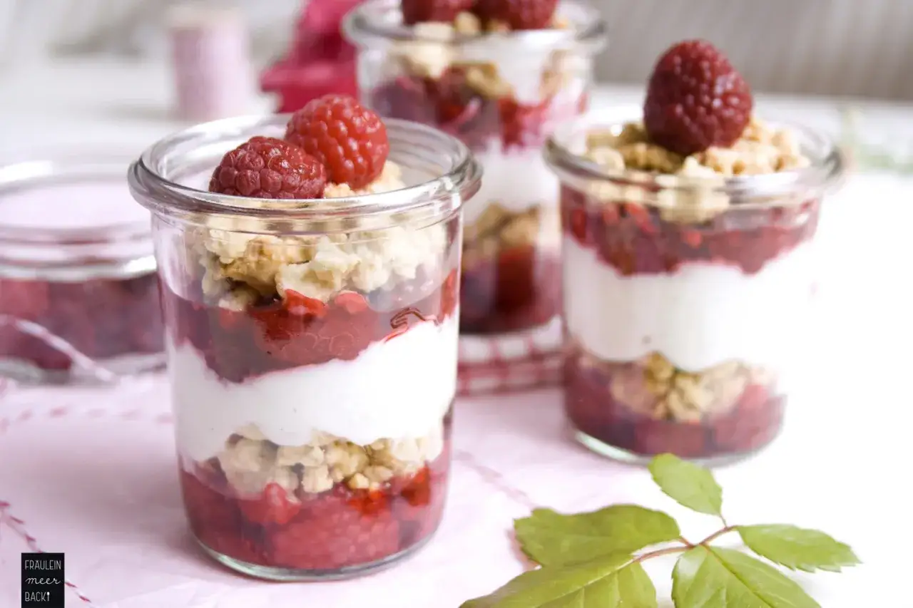 Himbeer Dessert im Glas: geschichtete Leckerei mit frischen Himbeeren, cremiger Joghurt-Schicht und knusprigem Crumble. Ein Genuss für Augen und Gaumen.