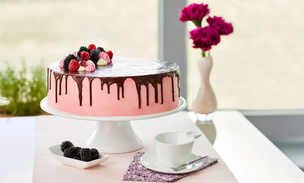 Rosa Torte mit Schokodrip & Beeren, ein Traum für geile Torten Rezepte! Daneben eine Tasse und Beeren.