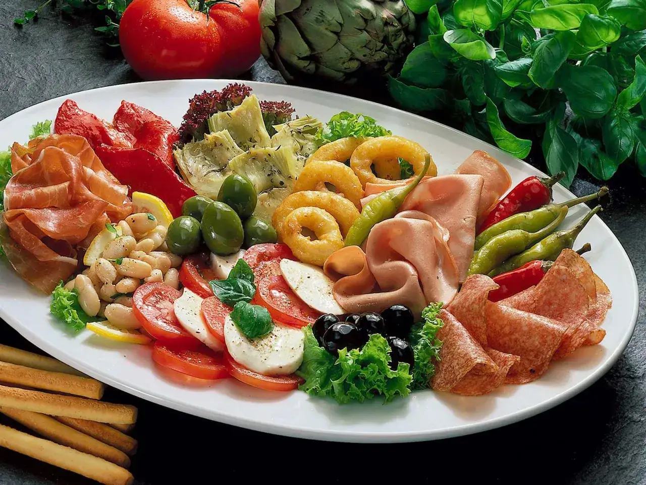 Antipastiplatte mit Schinken, Salami, Mozzarella, Tomaten, Oliven, Artischocken und Bohnen. Perfekt zum Antipasti selber machen für einen italienischen Abend.